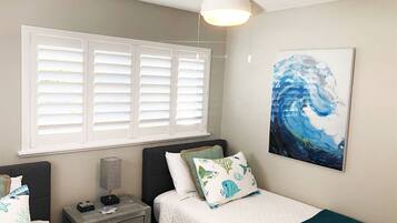 Une chambre avec deux lits, une table de chevet, une lampe et un tableau au mur.