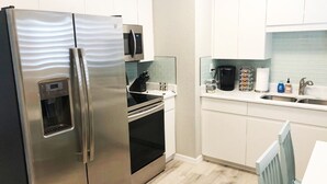 Una cocina moderna con electrodomésticos de acero inoxidable, horno integrado, microondas y cafetera.
