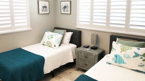 Un dormitorio con dos camas, una mesita de noche y un ventilador de techo.