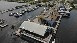Vista aérea de un puerto deportivo con varios muelles y barcos, rodeado de edificios residenciales y vegetación.