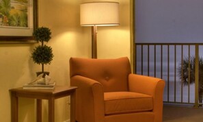 Relax in this inviting space with a comfortable armchair, side table, and floor lamp, plus a balcony with a view.