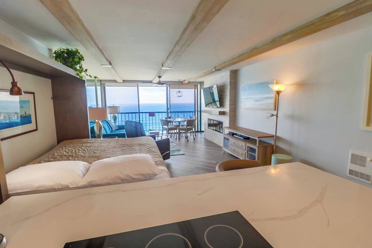 Une chambre d’hôtel avec un lit, un bureau, une télévision et un balcon donnant sur la mer.