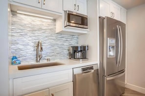 A modern kitchen with a stainless steel refrigerator, a built-in microwave, and a coffee maker. - Luxe Oceanfront view, murphy bed, parking and pool (San Diego)