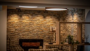 A cozy living room with a stone wall, a fireplace, and plaid furniture. - HomeHotel Salzberg (Berchtesgaden)