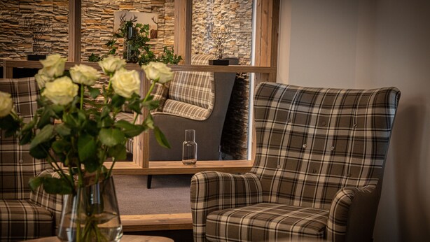 A cozy room with plaid-patterned chairs, a wooden table, and a vase of white flowers. - HomeHotel Salzberg (Berchtesgaden)