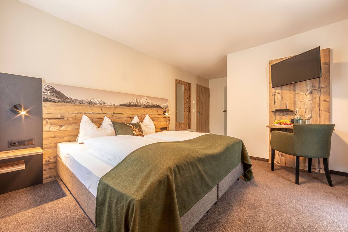 Une chambre à coucher comprenant un lit, un bureau, une chaise et un téléviseur fixé au mur.