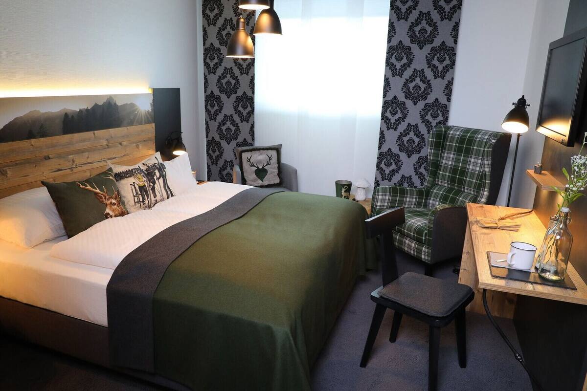 Une chambre d’hôtel avec un lit, un bureau et une chaise, une lampe et un cadre photo accroché au mur.