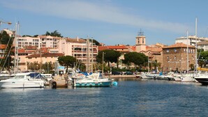 Un puerto deportivo con varias embarcaciones amarradas, una torre destacada y edificios al fondo.