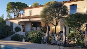 Una villa de estilo mediterráneo con piscina, mobiliario exterior y fachada de piedra.