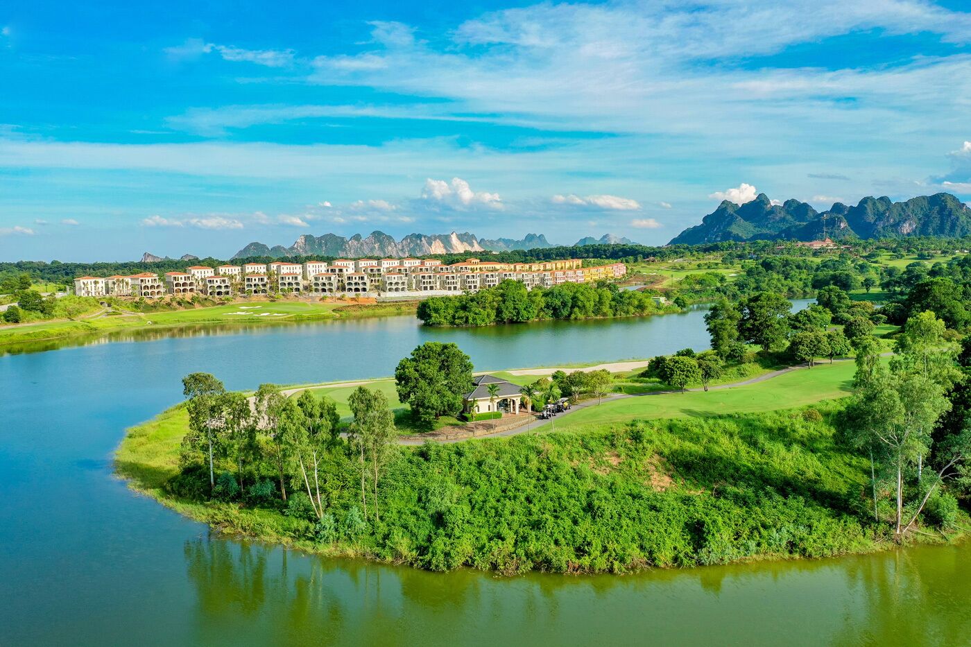 Een resort met meerdere gebouwen, een meer en een bergachtige achtergrond.