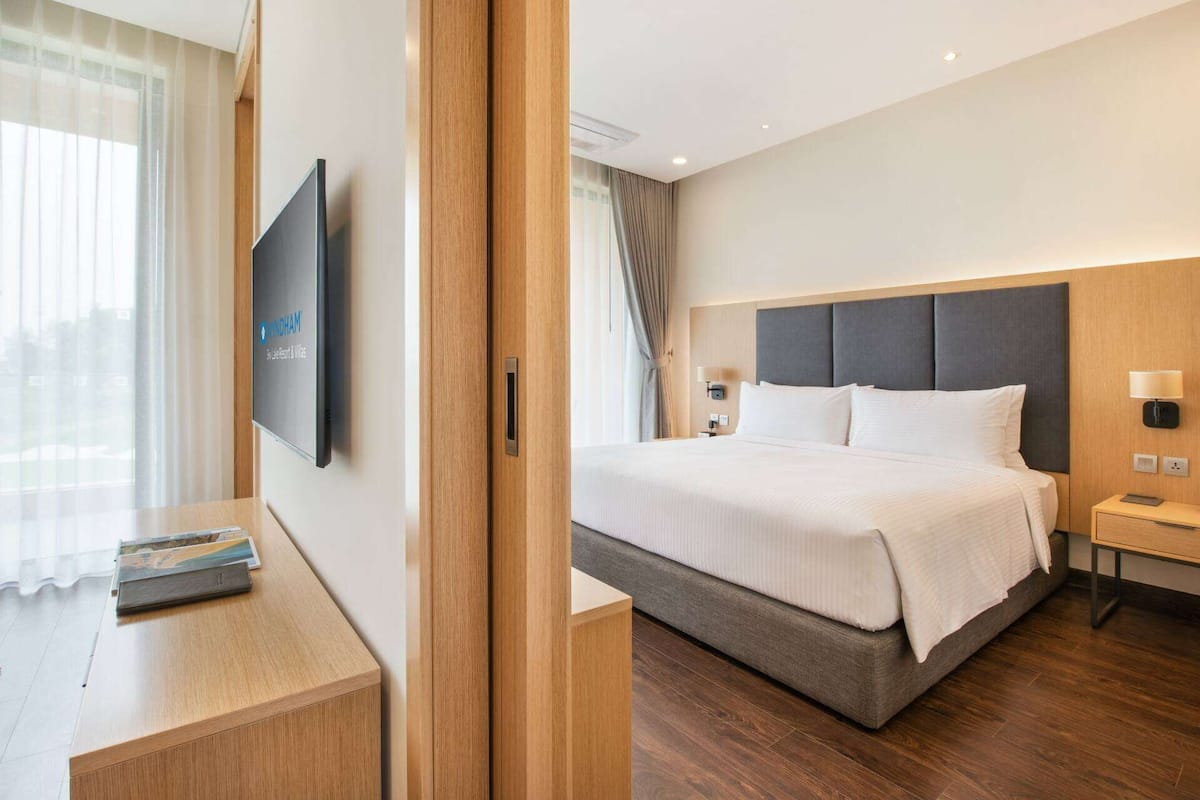 A hotel room with a large bed, a TV mounted on the wall, a bedside table, and a nightstand.