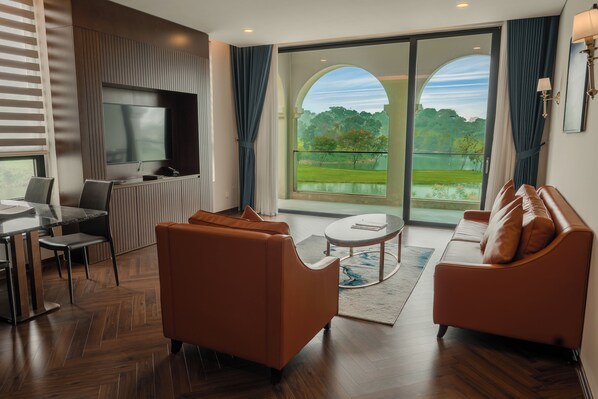 Una sala de estar moderna con un televisor de pantalla plana, sofás de cuero, un comedor y un ventanal con vistas a un parque.