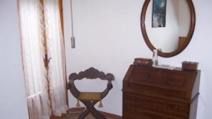 Une pièce comprenant une commode en bois, un miroir et une chaise.
