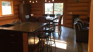 A log cabin interior with a kitchen, dining area, and seating space. - Golden Log House above the Valley (Golden)