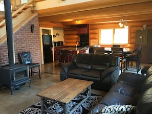 A cozy log cabin interior with a living room, dining area, and kitchen. - Golden Log House above the Valley (Golden)