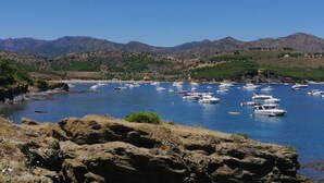 A coastal marina with boats docked, surrounded by rocky terrain and mountains in the background. - Comfortable Fisherman's House (Llançà)