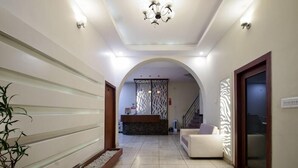 Un hall d’hôtel comprenant un comptoir d’accueil, un escalier et un espace détente.