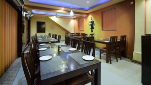 Un espace repas comprenant plusieurs tables et chaises, un plafond doté d’un éclairage encastré et un climatiseur fixé au mur.
