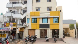 Un immeuble à plusieurs étages, doté d’une façade jaune et blanche, de nombreuses fenêtres et d’une entrée bien visible.