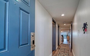 Un couloir avec une porte bleue, un tapis à motifs et un porte-clés fixé au mur.