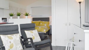 A modern, well-lit room with a bed, two armchairs, a small table, and a white wardrobe. - The Isle View Nest - UK13547 (Lower Harrapool, near Broadford)