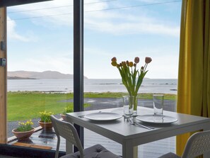 A dining table with plates, cutlery, and a vase of flowers. - The Isle View Nest - UK13547 (Lower Harrapool, near Broadford)