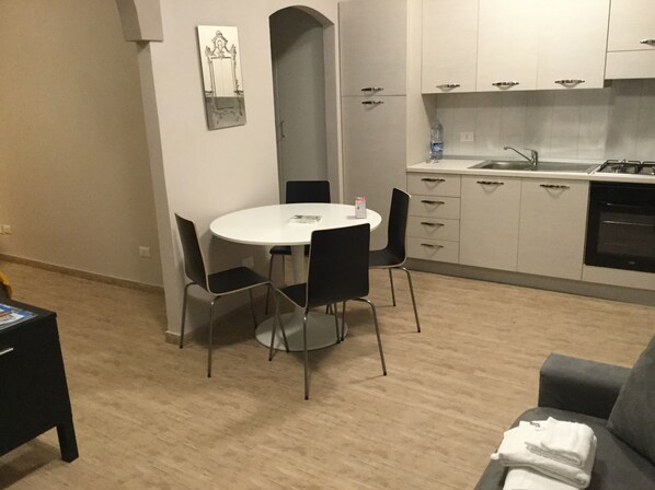 A compact living space with a dining area, kitchenette, and a sofa.