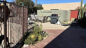 A patio area with outdoor furniture, a grill, and a cactus garden.