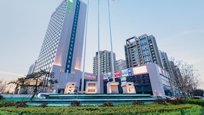 A modern high-rise building with multiple floors, large windows, and a prominent entrance area with steps leading up to it. - Holiday Inn Express Liaocheng Chiping by IHG (Liaocheng)