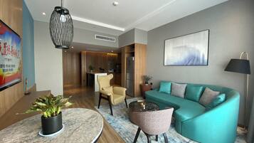 Una sala de estar moderna con un sofá verde azulado, una mesa de centro redonda y una silla. Hay un cuadro en la pared y una planta en maceta sobre la mesa.