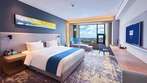 A modern hotel room with a large bed, a desk, a chair, a TV, and a city view. - Holiday Inn Express Liaocheng Chiping by IHG (Liaocheng)