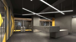 A modern gym interior with geometric lighting, concrete reception desk, and industrial design elements.