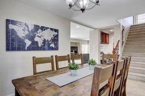 Een eetruimte met een houten tafel, stoelen, een wereldkaart aan de muur en een trap.