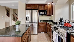 A modern kitchen with stainless steel appliances, wooden cabinets, and a granite countertop. - Pool/Spa-15 min from ✈️ & strip. Smart TVs Close to shopping 🍔 freeway... (Henderson)