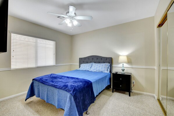 A bedroom with a bed, nightstand, lamp, ceiling fan, and window with blinds. - Pool/Spa-15 min from ✈️ & strip. Smart TVs Close to shopping 🍔 freeway... (Henderson)