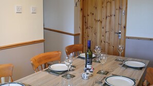 A dining table set for four with plates, cutlery, and wine glasses. - 4 bedroom accommodation in Fenwick, near Kilmarnock (Fenwick, near Kilmarnock)