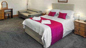 A neatly arranged bedroom with a bed, a desk, a chair, and a floor lamp. - 4 bedroom accommodation in Fenwick, near Kilmarnock (Fenwick, near Kilmarnock)