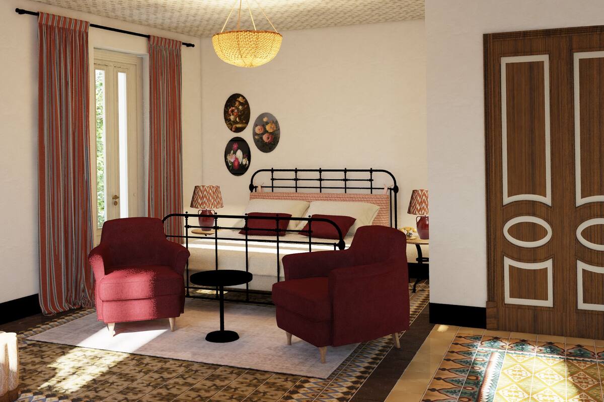 A bedroom with a bed, two armchairs, a small table, a lamp, and a door.