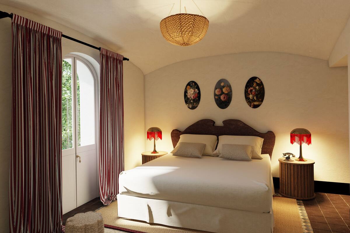 A bedroom with a large bed, two bedside tables with lamps, a woven ceiling light, and three wall-mounted flower paintings.