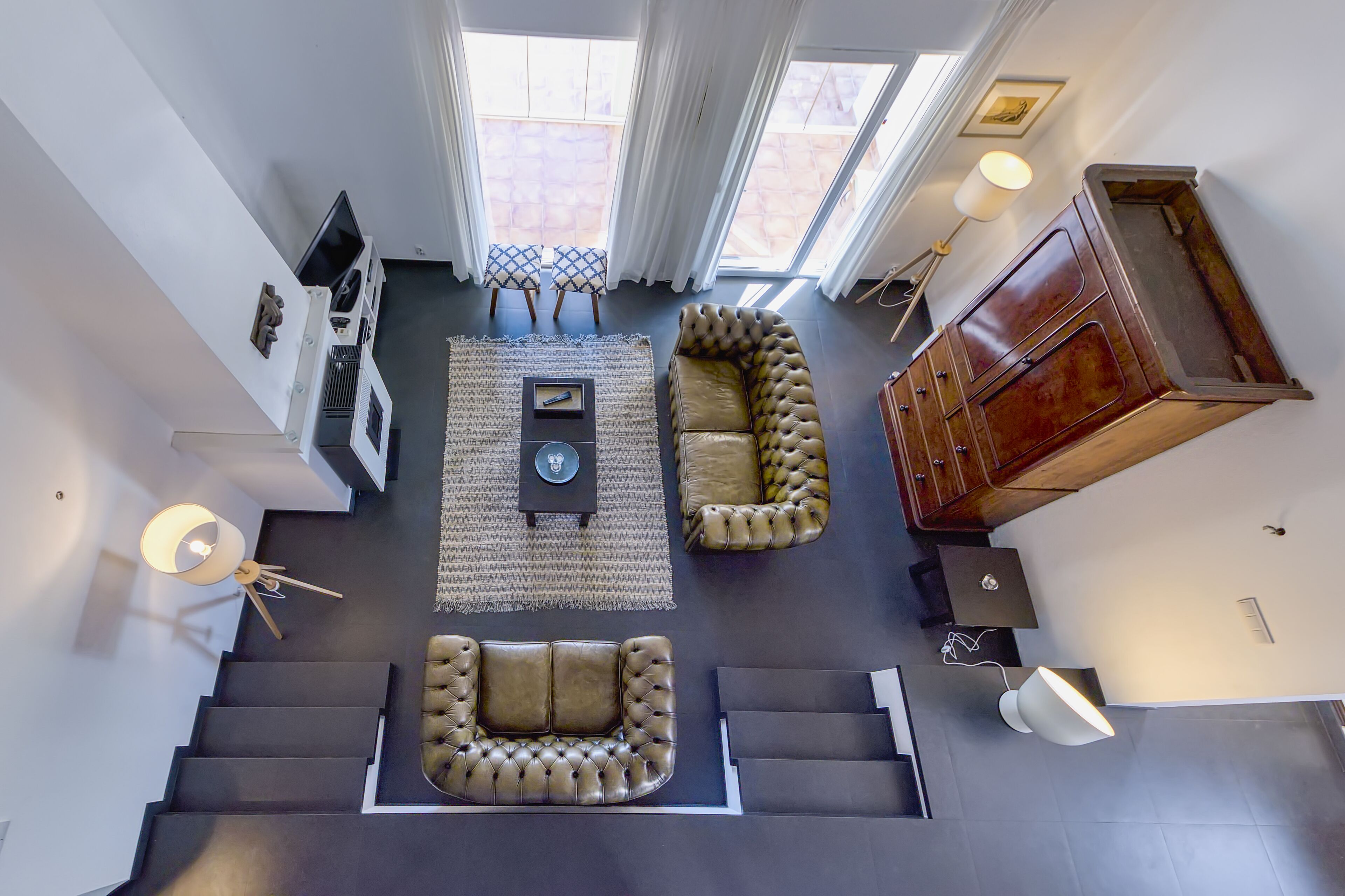 A spacious living area with a high ceiling, a large window, a sofa, a coffee table, and a cabinet.