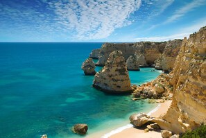 A coastal landscape with clear blue waters, rocky cliffs, and a sandy beach. - Casa Bodil, villa for 8 with private pool (Praia do Carvoeiro)