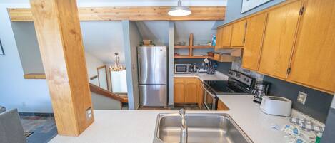 A kitchen with wooden cabinets, stainless steel appliances, and a white countertop.