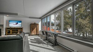 A modern living room with a large window, a television, a sofa, and a dining table. - Decatur 1782 (Keystone)