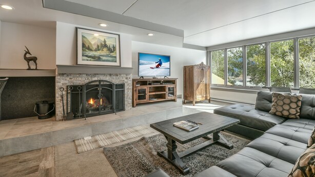 A modern living room with a fireplace, a large window, and a comfortable seating area. - Decatur 1782 (Keystone)