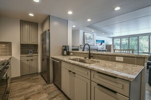 A modern kitchen with granite countertops, stainless steel appliances, and ample natural light from large windows.