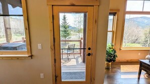 Una puerta de madera con un panel de vidrio que da a una terraza exterior con un banco. Un letrero sobre la puerta dice "Keystone, Colorado Elevation 9,280".
