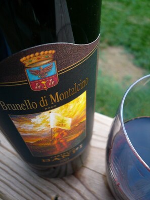 A bottle of Brunello di Montalcino wine with a label featuring a coat of arms and a scenic landscape. - La Rosa Canina [Tuscany cottage] (Cana)