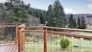 A wooden deck with a metal railing overlooking a grassy area with trees. - 3 bedroom accommodation in Glenlivet, near Dufftown (Glenlivet, near Dufftown)
