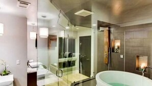 A modern bathroom with a glass shower enclosure, a freestanding bathtub, and a small sink area. - Surfrider at the Del Mar Beach Colony (Del Mar)