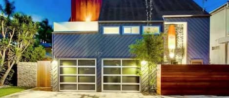 Una casa moderna con garaje, un muro de piedra y una cerca de madera.